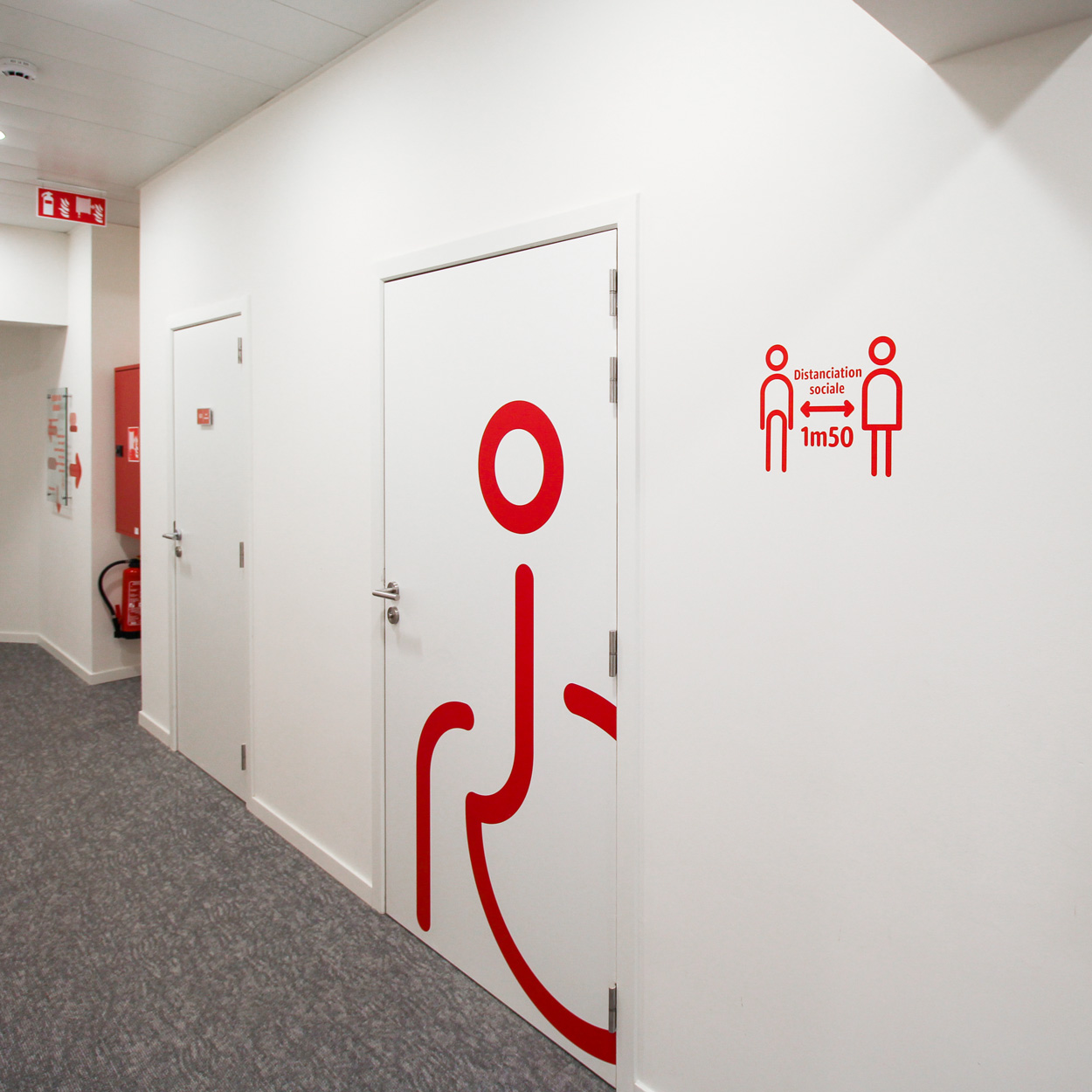 Couloir de Synergies Wallonie avec pictogramme PMR rouge en vinyle découpé sur porte