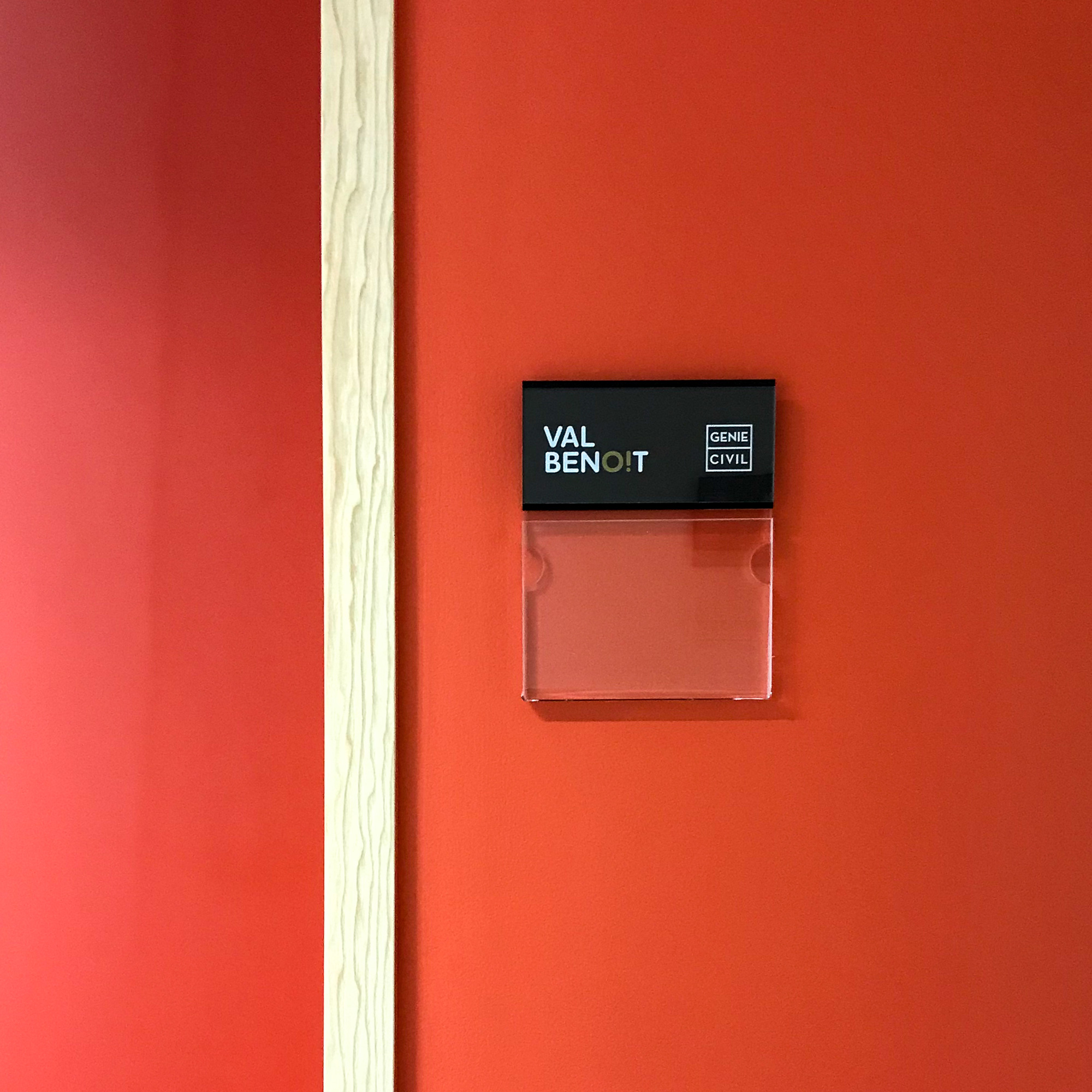 close up sur plaque de porte skwizmi sur mur coloré rouge