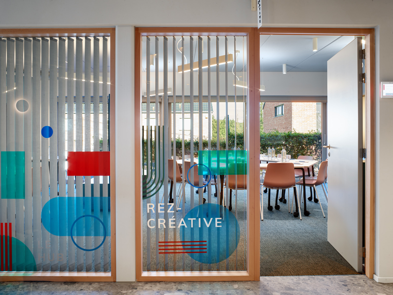zoom sur les formes de couleur de l'habillage graphique réalisé sur les cloisons vitrées de la salle de réunion rez-créative du Hub