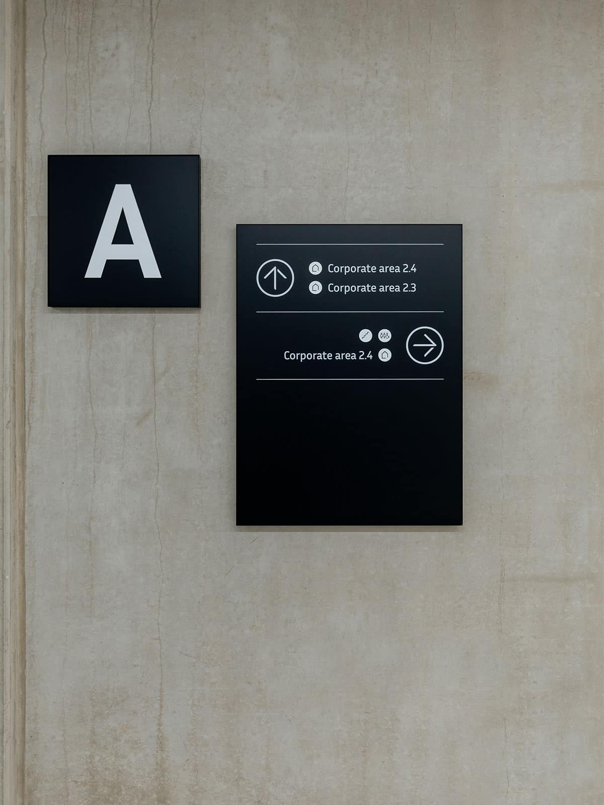 Gros plan sur une balise directionnelle du Legiapark composée d'une boc en aluminium noir carré qui indique le bâtiment dans lequel on se trouve (le A) et puis une seconde box rectangulaire qui reprends les différentes directions et services