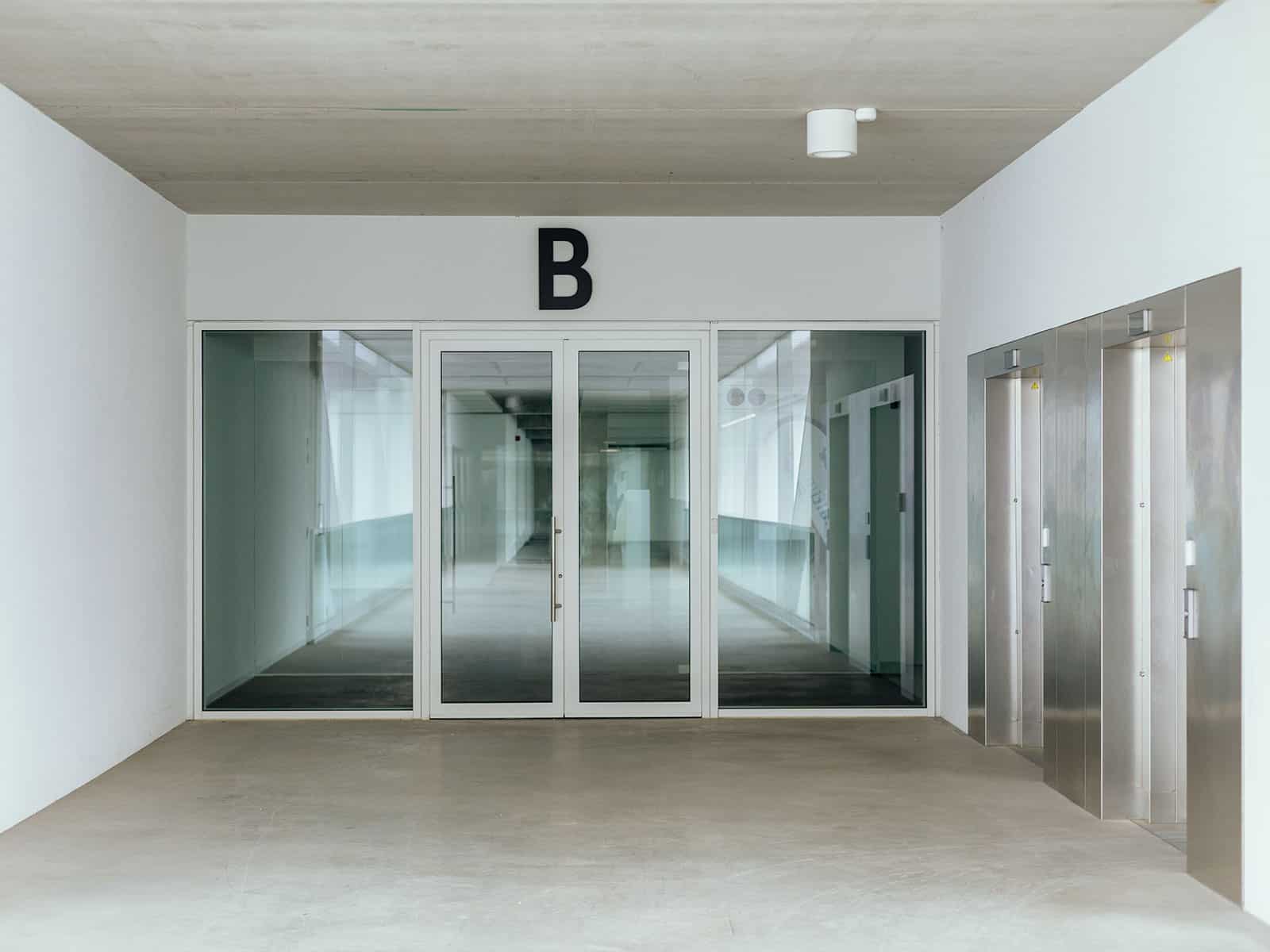 Vue depuis la passerelle, située entre les deux bâtiments, au deuxième étage, vers le batiment B identifié à l'aide d'une lettre géante